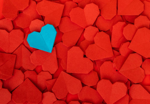istock Lots of red heart shape papers with a blue one on them 2191072448