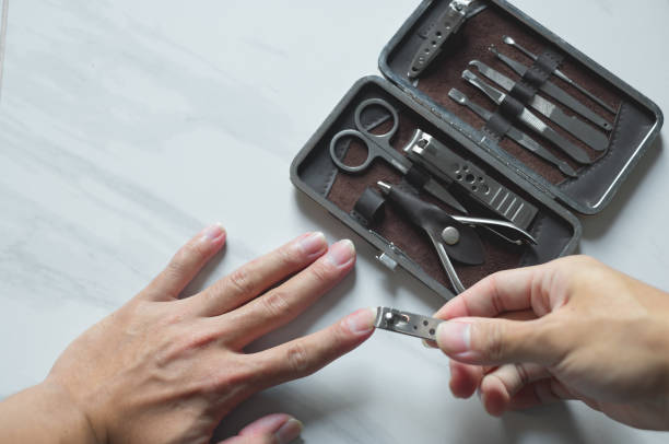 istock Holding hand cutting nails manicure and pedicure tool set concept, cosmetic accessories for nails, scissors, pusher cuticle and nail file, cleaning nails for protection dirt bacteria in nails. 2191081229