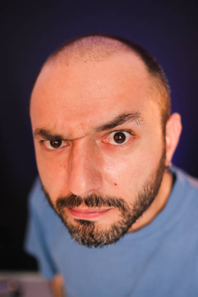 A young man with piercings looks at the camera with surprise