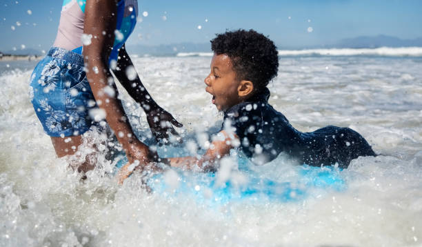 istock Excited boy surfing with mother at beach 2191086648
