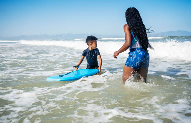 istock Mother and son having fun with bodyboard at beach 2191086677