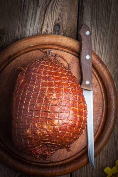 Whole ham on a wooden table, selective focus.