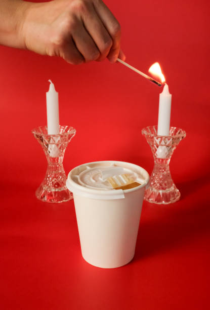 Hand Lighting Candle in Elegant Crystal with To-go Coffee Cup in Foreground - Modern concept for Valentines Day