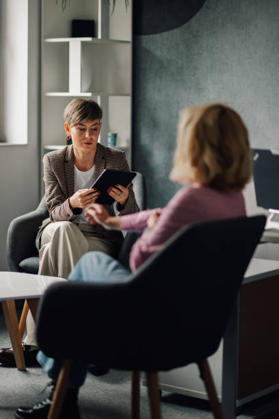 Two businesswomen discussing using digital tablet in modern office