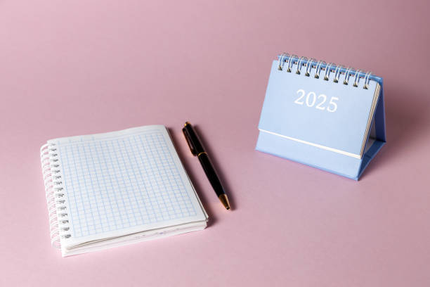 istock A desktop calendar for 2025, a notebook and a black ballpoint pen on a pink background. 2191094194