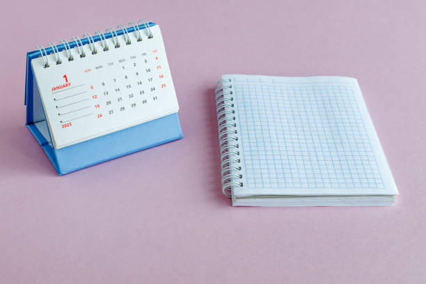 istock A desktop calendar for 2025 and an open notebook on a pink background. 2191094231