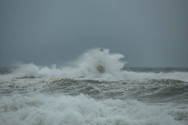 Ocean waves crashing against a lighthouse during a powerful storm at sea