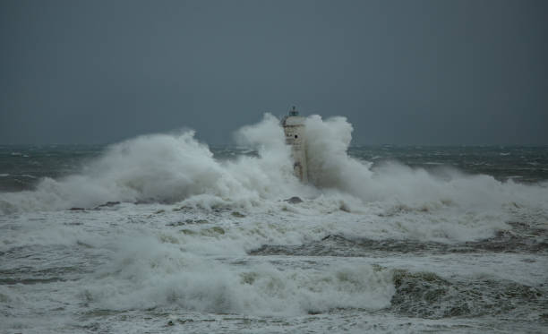 istock Lighthouse standing strong against powerful ocean waves during storm 2191096744