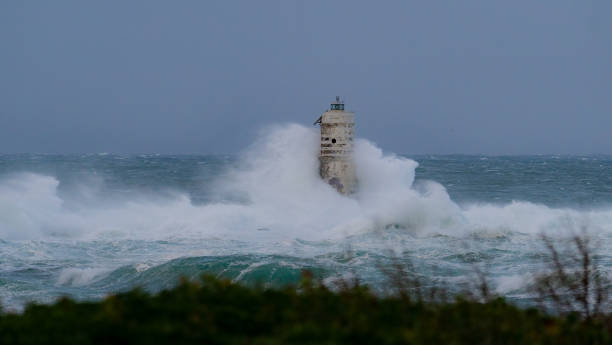 istock Lighthouse standing strong against powerful ocean waves during storm 2191096838