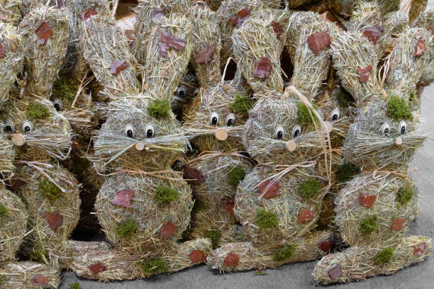 Easter decorative bunnies made from hay stand in rows, ready for sale. Handmade