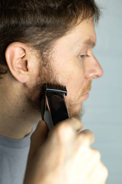istock A man trims his beard with a trimmer. An electric razor trimming a beard. 2191097195