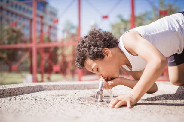 Close-Up Of Girl Drinking Water From Faucet Outdoors
