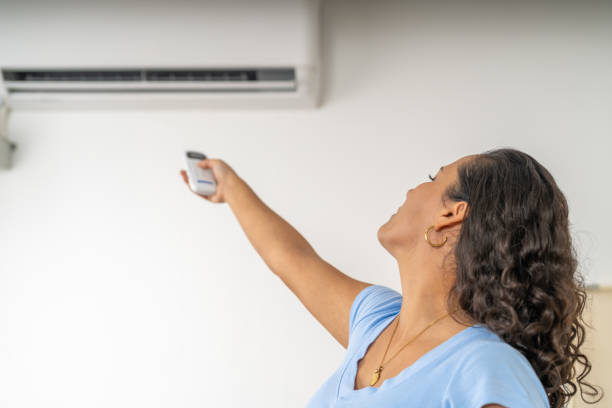 istock Woman pointing remote control at air conditioner feeling heat 2191114182