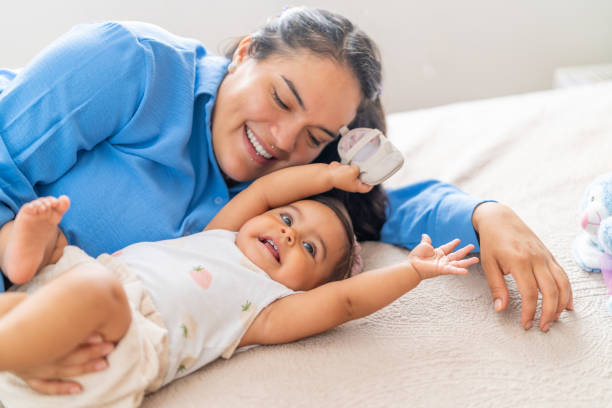 istock Happy mother lying on bed playing with baby daughter 2191116627