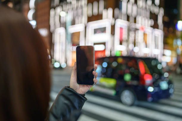 Japanese woman using mobile phone next to crosswalk.