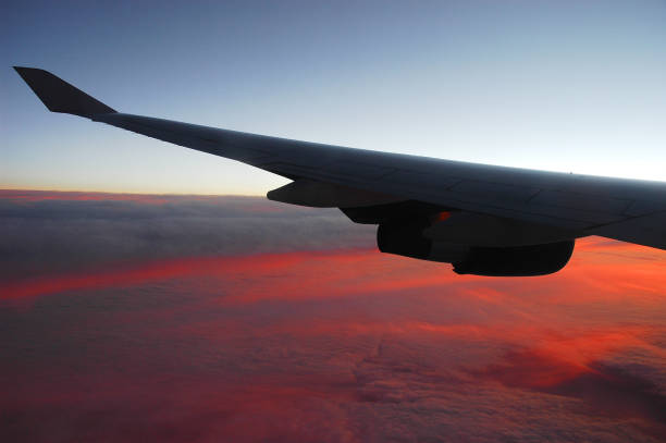 red sunlight spreading on aerial cloud below airplane wing
