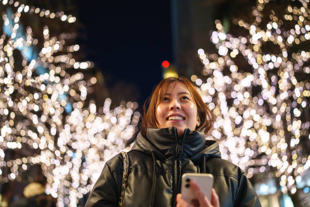 istock Japanese woman using mobile phone in illuminated city streets. 2191121196