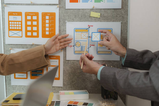 istock A team of web developers discusses how to best organize a website layout. They share ideas on how to best optimize a digital product, ux ui team is working together in the office 2191124019