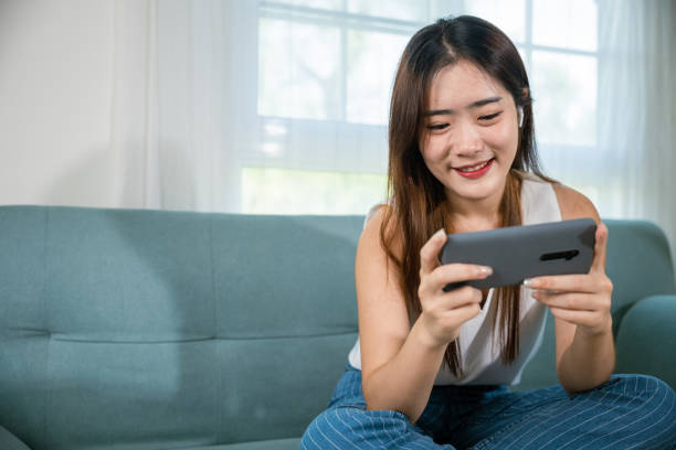 istock woman sitting on sofa using mobile smart phone at living room 2191129387