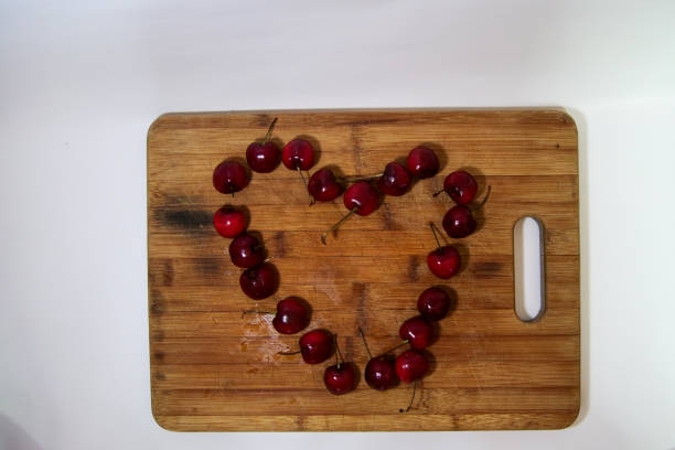 Fresh red cherries on a brown wooden cutting board. Heart shaped
