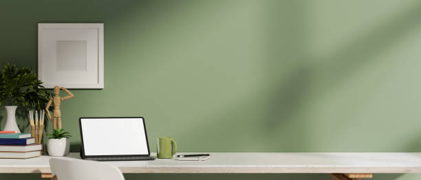istock A digital tablet with a white screen mockup and decor on a table against a green wall in a room. 2191136988