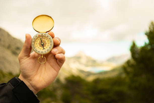 istock Male hand holding a compass on the mountain with grey clouds in the background 2191137675