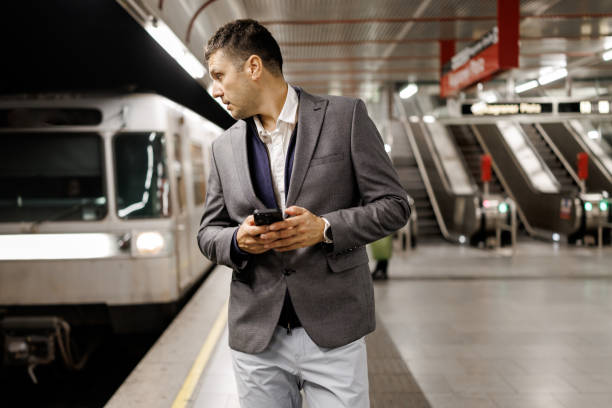 istock Businessman texting on mobile phone while waiting for train on subway station 2191137717