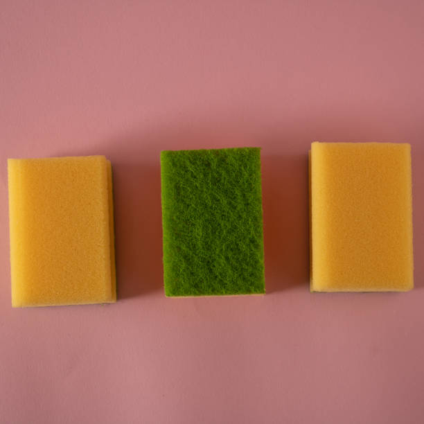 istock Three yellow and green kitchen sponges on a pink tablecloth 2191142007