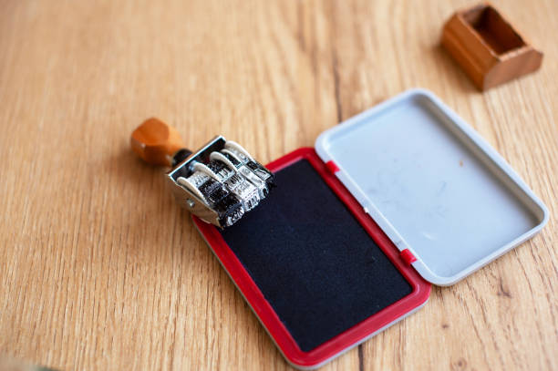 A classic office date stamp next to its accompanying red ink pad, lying open on a wooden desktop