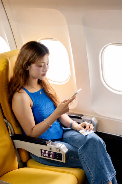 istock An Asian female passenger uses her smartphone to read text messages during a flight while sitting in a window seat during a flight. 2191143376