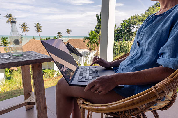 istock Person Relaxing on Patio with Laptop Overlooking Tropical View 2191145771
