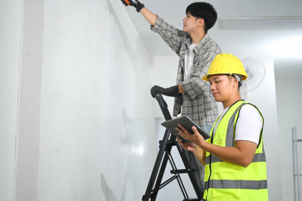 istock Asian supervisor with digital tablet overseeing painting work at construction site 2191148578
