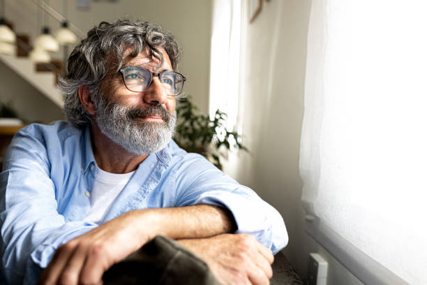 Senior man relaxing and looking out the window at home