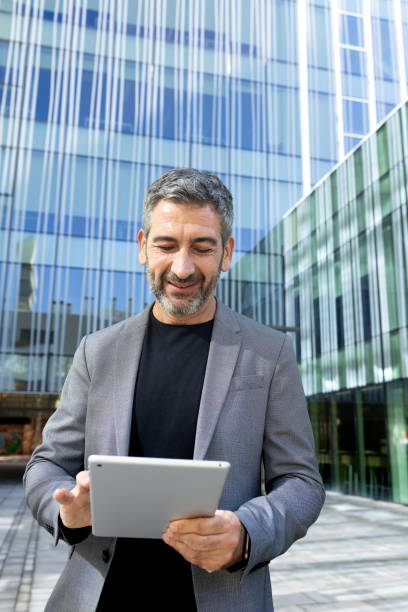 istock Smiling businessman using digital tablet in front of office building 2191148938