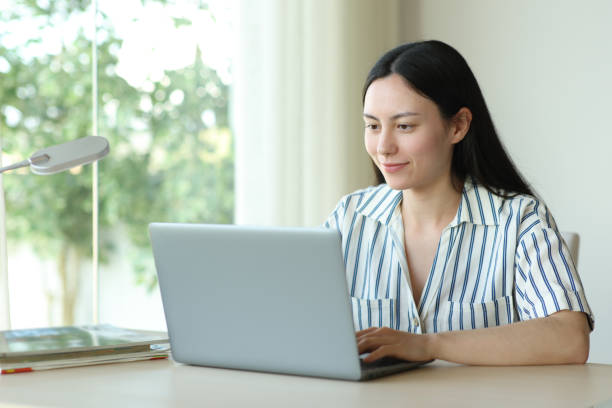 istock Asian woman using laptop on a desk at home 2191150864
