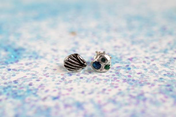 istock Silver handmade earrings with gemstones in shell and starfish shapes on sparkly background. 2191152170
