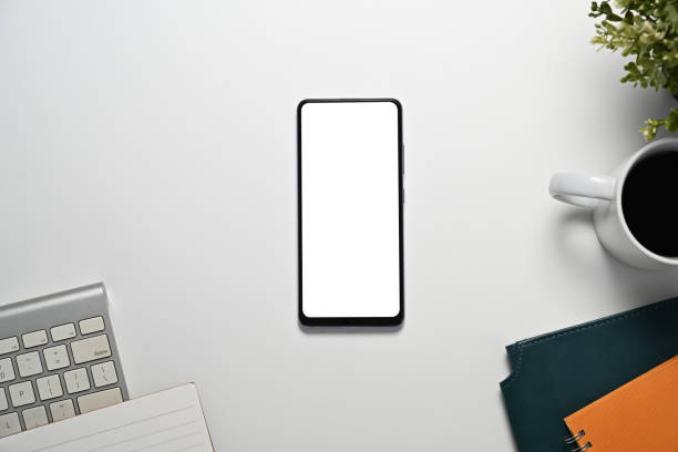 istock White office desk with blank smartphone screen, keyboard and notebooks 2191152536