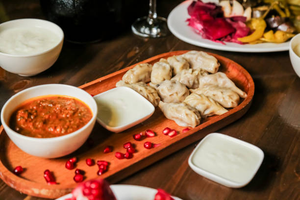 istock Delicious dumplings served with sauce and garnishes at a dining table 2191152983