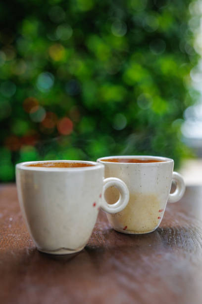 Beige ceramic espresso cups on the wooden table outdoors, coffee drinking culture