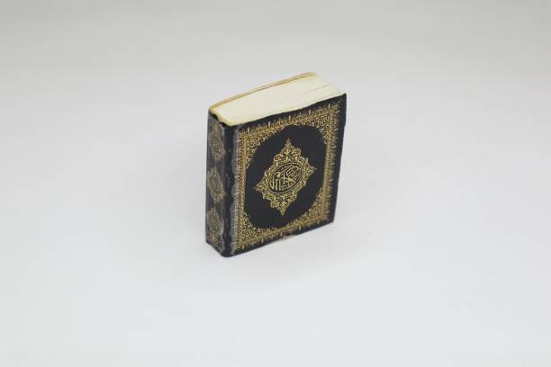 A small, black Quran is shown against a white background.