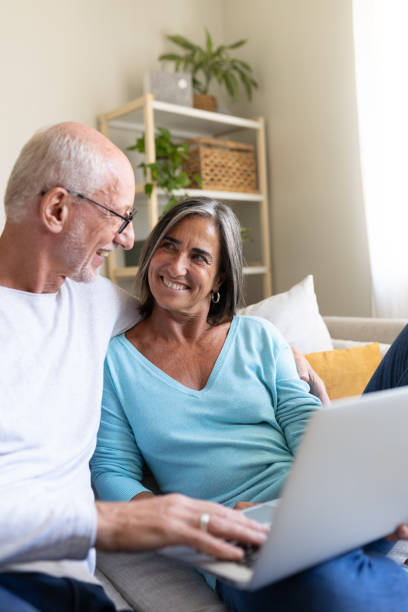 istock Happy senior couple relaxing on sofa using laptop at home 2191155481