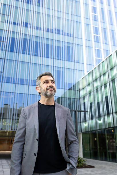 istock Confident businessman looking up while standing near office building 2191155518