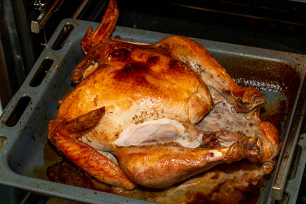 Juicy turkey is roasted to golden perfection in a baking pan, ready for a festive meal. The skin is crispy, and the meat looks tender and flavorful.