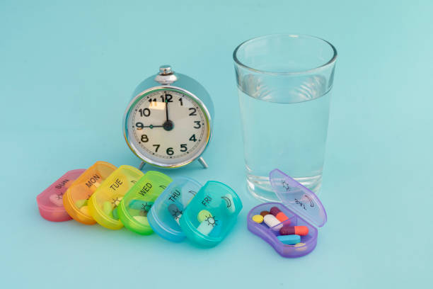 istock Pills in storage boxes for whole week with alarm clock on blue background 2191156092