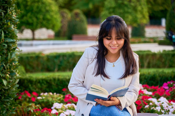 istock Latina woman reading a book while sitting in a garden 2191156589