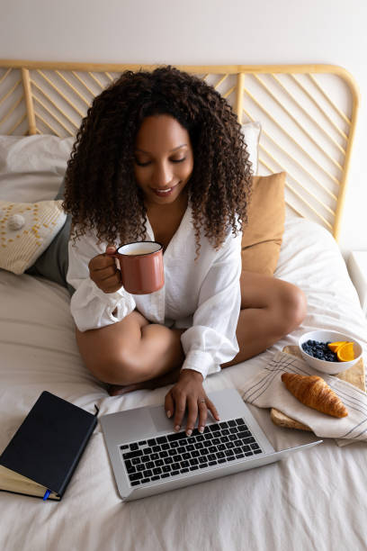 istock Young woman working remotely from home drinking coffee in bed 2191158456