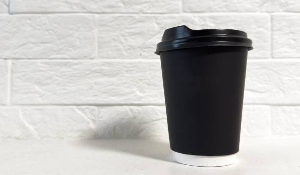 istock Closeup front view disposable black paper coffee cup with head isolated on white background 2191159462