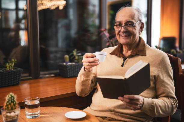 istock Relaxed senior man drinking coffee and reading a book in cafe 2191160906