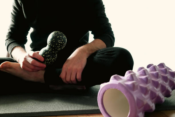 istock Physical Therapy. Man is exercising at home. Exercise with ball and foam roller for myofascial release. Equipment for MFR. Tools for self-massage. 2191166224