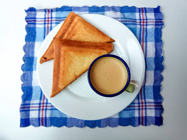 Triangular toasts and a cup of coffee, served on a white plate. Coffee inside a green enamel mug. Simple and classic style of breakfast